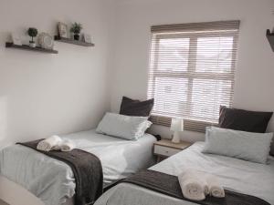 two twin beds in a room with a window at Modern 2 bedroom apartment close to shops & beach in Gordonʼs Bay