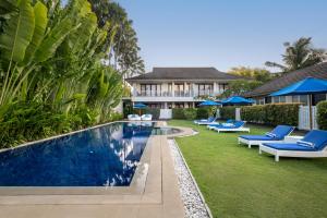a backyard with a swimming pool and chairs and a house at Montigo Resorts Seminyak in Seminyak