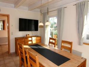 a dining room with a table and a flat screen tv at Semi-detached house Strandhaus I, Trassenheide in Trassenheide