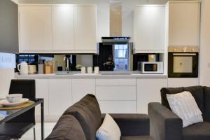 a kitchen with white cabinets and a couch and a table at 3 Bed Apartment in Wigan in Wigan