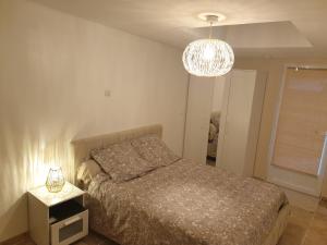 a bedroom with a bed and a chandelier at The Cosy House - votre havre de paix avec jardin privé in Lisses