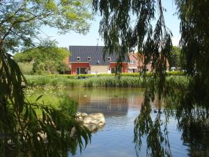 vistas a un estanque con una casa en el fondo en Holiday home Klinger, en Todendorf auf Fehmarn