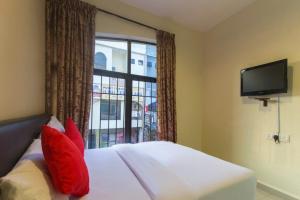 a bedroom with a bed with red pillows and a window at Ferringhi Inn Hotel in Batu Ferringhi