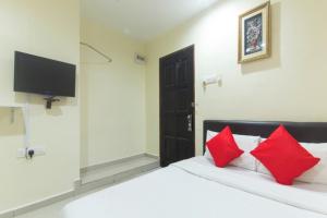 a bedroom with a bed with red pillows and a television at Ferringhi Inn Hotel in Batu Ferringhi