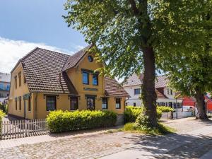 ein gelbes Haus mit einem schwarzen Dach und einem Baum in der Unterkunft Holiday apartment coastal love in Wustrow