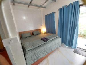 Cette petite chambre comprend un lit avec des rideaux bleus. dans l'établissement AiOonHomestay, à Ban Bang Bao