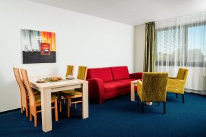 sala de estar con sofá rojo, mesa y sillas en Apartmanovy dom Familia Smokovec en Starý Smokovec