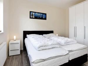 una camera da letto con un grande letto con lenzuola bianche di 6 person holiday home in Gro enbrode a Grossenbrode