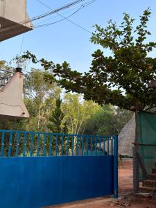 Una cerca azul con un árbol encima. en Lotus Garden - Near Matrimandir Center Auroville en Auroville
