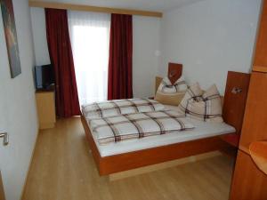 1 dormitorio con cama con sábanas a cuadros y ventana en Ferienwohnung Rainer, en Leogang