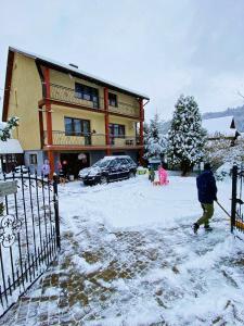 a person walking in the snow in front of a building at Noclegi pod bukami in Rajcza