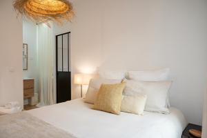 a bedroom with a white bed with white pillows at La Tropézienne - appartement au cœur du village in Saint-Tropez
