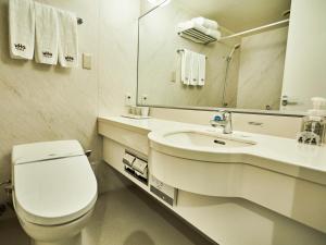 a white bathroom with a toilet and a sink at Kansai Airport Washington Hotel in Izumi-Sano