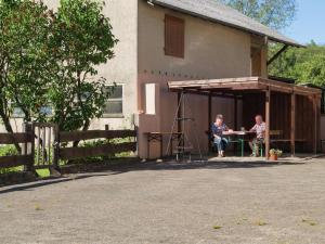 two people sitting at a table outside of a house at Spacious Holiday Home in Ulmen near the centre in Ulmen