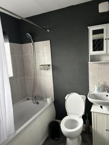 a bathroom with a toilet and a tub and a sink at Large 5-Bed House in Leeds Fits 10 Free Parking in Leeds