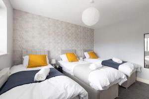 リーズにあるLarge 5-Bed House in Leeds Fits 10 Free Parkingの黄色と白のベッド3台が備わる客室です。
