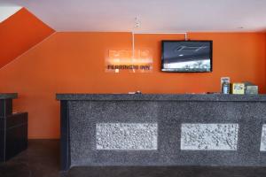 a bar with a flat screen tv on an orange wall at Ferringhi Inn Hotel in Batu Ferringhi