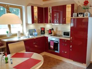 Pleasant apartment in Schwielowsee في شيلووسي: مطبخ مع دواليب حمراء وطاولة ومغسلة