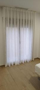 cortina blanca en una habitación con suelo de madera en SM Apartments en Lleida
