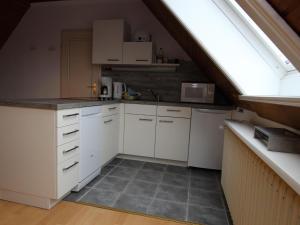 an attic kitchen with white cabinets and a window at Apartment in Westerland in Westerland