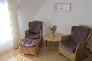 duas cadeiras e uma mesa com um vaso de flores em Apartment in Westerland em Westerland