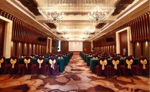uma grande sala com fileiras de mesas e cadeiras em Hotel Fortune em Shunde