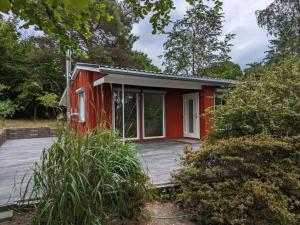 ein rotes winziges Haus mit einer Holzterrasse in der Unterkunft Holiday home Werder Havel in Werder
