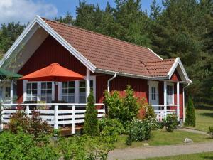 a red house with a white fence and an umbrella at Holiday home Vogelsang in Userin