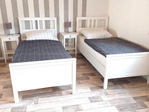 two white beds in a room with two night stands at Holiday Home in idyllic Ziesar near the Natuurpark in Gladau