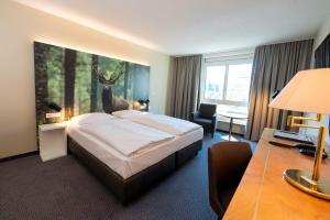 ein Hotelzimmer mit einem Bett mit einem Hirschgemälde an der Wand in der Unterkunft Erikson Hotel in Sindelfingen