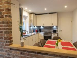 a kitchen with a dining table and a kitchen with white cabinets at North Sea holiday home Zinnäcker in Almdorf