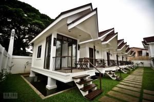 a building with a row of benches on the grass at Cleon Villas Pension in Puerto Princesa City