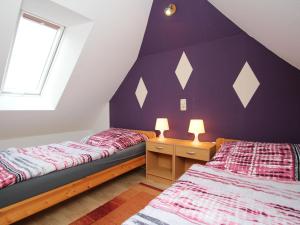 Schlafzimmer im Dachgeschoss mit 2 Betten und einer lila Wand in der Unterkunft Holiday House Ganesha, Utarp in Utarp