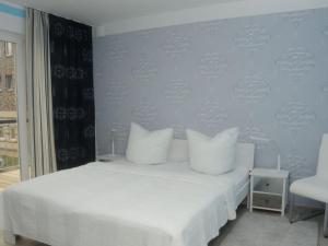 een wit bed met witte kussens in een slaapkamer bij Holiday apartment "Sun Catcher" in Dierhagen