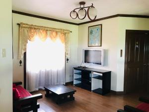 ein Wohnzimmer mit einem TV und einem Tisch in der Unterkunft OYO 1068 Villa Adelle At Silang in Maitim