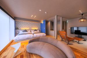 a bedroom with two beds and a couch and a tv at SAZANAMI LAKE FRONT in Fujikawaguchiko