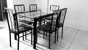 une table en verre avec quatre chaises et un plateau en verre dans l'établissement Mejia Gate 3, à Ormoc