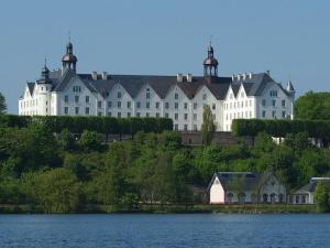 a large white building on a hill next to a body of water at Art Nouveau villa am See in Ascheberg