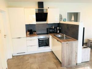 a kitchen with white cabinets and a sink at Holiday apartment starfish in Butjadingen +15 photos