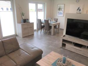 a living room with a couch and a flat screen tv at Holiday apartment starfish in Butjadingen