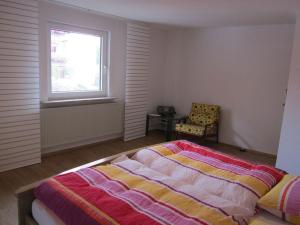 a bedroom with a bed and a window and a chair at Holiday apartment Heitmann in Hilders