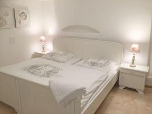 1 cama blanca con 2 mesitas de noche y 2 lámparas en Holiday apartment at Castle I, en Brakel