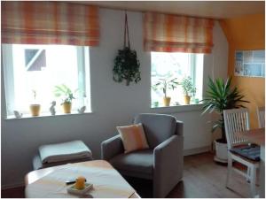 un soggiorno con sedia, tavolo e finestre di Holiday apartment Grohnert a Lubecca