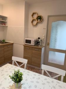 eine Küche mit einem Tisch, 2 Stühlen und einer Mikrowelle in der Unterkunft Belvárosi Levendula Apartman Gyula in Gyula