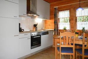 eine Küche mit weißen Schränken und einem Holztisch mit Stühlen in der Unterkunft Blockhouse in the Fuchsbau Bad Sachsa in Bad Sachsa