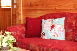 eine rote Couch mit einem Schmetterlingskissen drauf in der Unterkunft Blockhouse in the Fuchsbau Bad Sachsa in Bad Sachsa