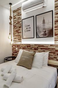 1 dormitorio con cama blanca y pared de ladrillo en Apartamentos Estrecho, en Madrid