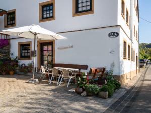 a table and chairs and an umbrella in front of a building at A modern apartment in the Hunsr ck region s romantic Drohn Valley in Merschbach