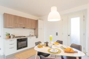 a white kitchen with a table with food on it at Ponente Balcony & Garden by Rent All Como in Gravedona