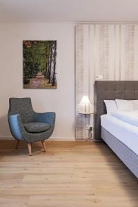 ein Schlafzimmer mit einem Stuhl neben einem Bett in der Unterkunft Holly GmbH Ferienwohnungen in Bad Alexandersbad